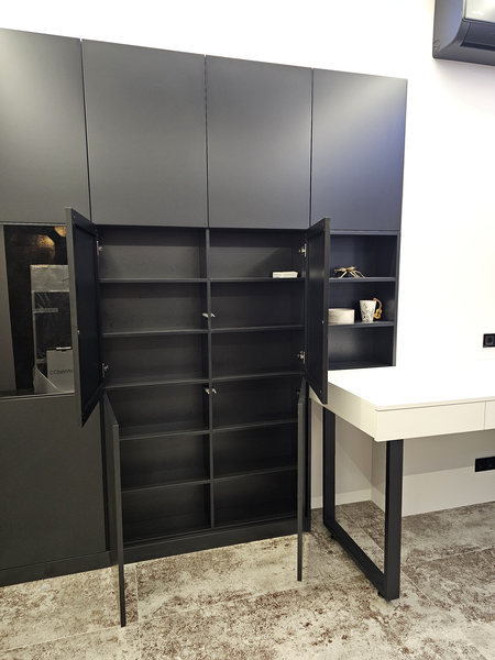 Корпусный шкаф Корпусный шкаф с распашными фасадами в чёрном матовом исполнении: центральная секция с открытыми дверями демонстрирует внутреннее наполнение с полками для аккуратного хранения, боковая открытая ниша используется как декоративная витрина, рядом интегрирован рабочий стол.