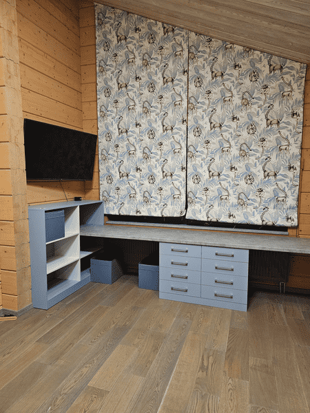Рабочее место Рабочее место в детской комнате с индивидуально изготовленной корпусной мебелью: столешница во всю стену, выдвижные ящики повышенной вместимости и открытые полки, спроектированные под наклон потолка.