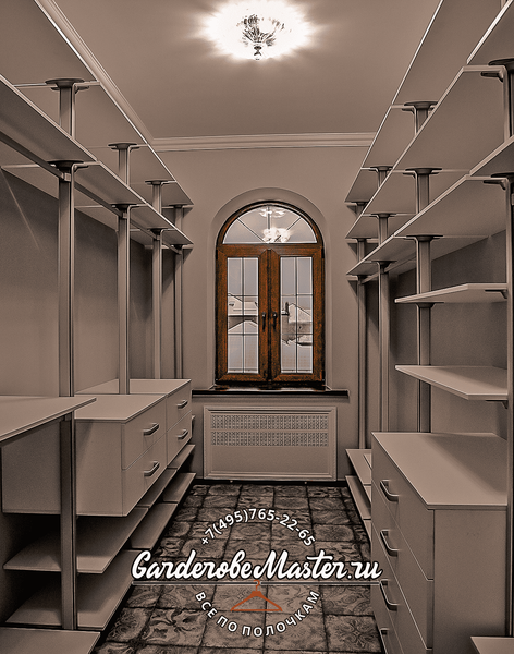 Открытая гардеробная система GarderobeMaster с симметричной планировкой, металлическими стойками от пола до потолка, выдвижными ящиками и полками по обе стороны, центральным окном с арочным проёмом и классическим потолочным освещением