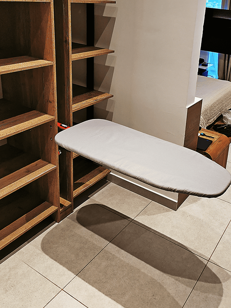 Гардеробная система на заказ с натуральным деревом и чёрным металлом, оснащённая встроенной гладильной доской, глубокими секциями для хранения и архитектурной компоновкой без лишних элементов.