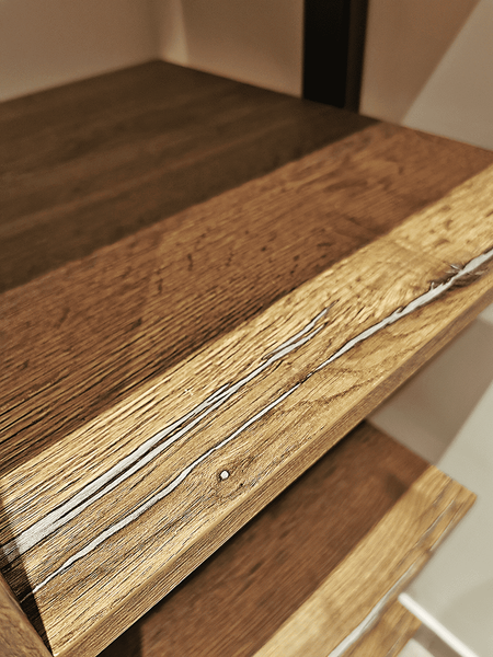 Открытая гардеробная система в индустриальном стиле с массивными деревянными полками, чёрными металлическими стойками и акцентом на фактуру натурального дерева, подчёркивающую ручную обработку и архитектурную жёсткость конструкции