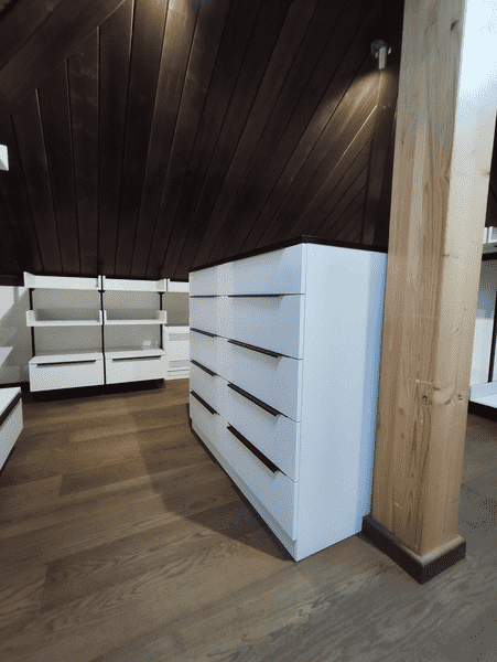 Гардеробная система под мансардной крышей с островным комодом на 6 выдвижных ящиков, напольными модулями хранения и верхними полками по периметру