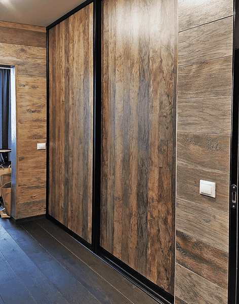Раздвижные двери гардеробной в отделке под дерево с чёрным профилем, интегрированные в интерьер коридора