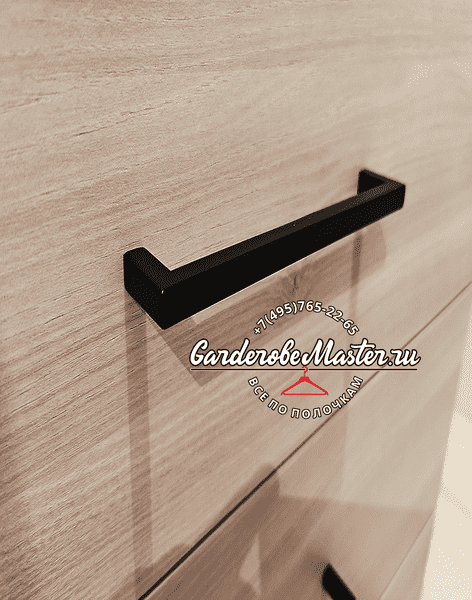 Деталь мебельной Деталь мебельной фурнитуры — чёрная металлическая ручка на фасаде выдвижного ящика из текстурированного ЛДСП, акцент на качестве материалов и аккуратной сборке