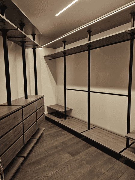 Гардеробная комната Гардеробная комната с открытыми секциями и штангами для одежды, строгий современный стиль.