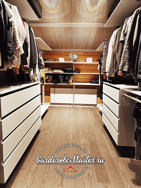 Проходная гардеробная Проходная гардеробная под мансардной крышей с симметричной компоновкой, двумя блоками комодов, зонами для длинной и короткой одежды и верхними полками